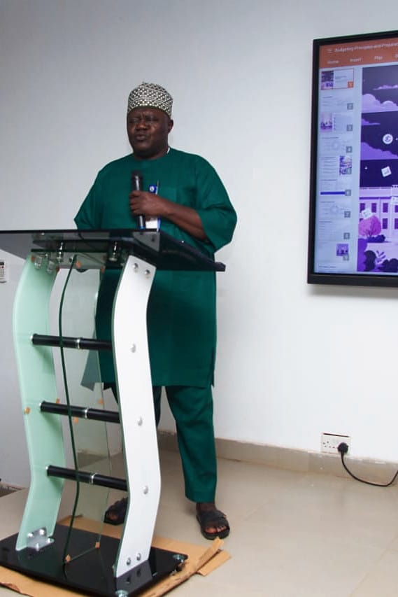 A facilitator presenting beside a screen showing a slide on budget preparation.